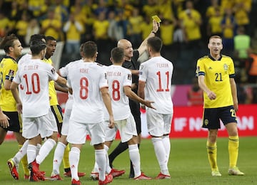 El árbitro Anthony Taylor enseña la cartulina amarilla a Dejan Kulusevski en medio de las protestas de los jugadores españoles.