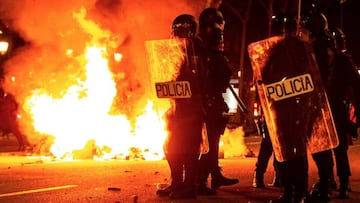 Varioagentes de polic&iacute;a, en pie al lado de una hoguera encendida por los manifestantes durante los distrubrioen el centro de Barcelona posteriores a la sentencia del &#039;proc&eacute;s&#039;.