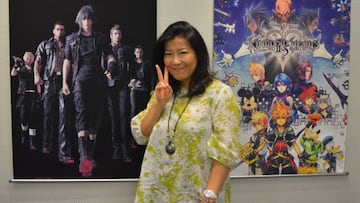 Yoko Shimomura posa junto con los pósters de Kingdom Hearts y Final Fantasy XV, dos de sus obras más célebres.