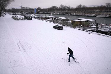 Una persona esquía a orillas del río Sena tras una nevada.
