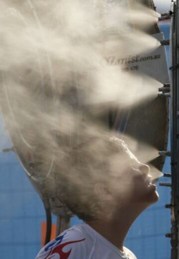 Un aficionado se refresca delante de un ventilador en el Abierto de 2014 de Australia en Melbourne