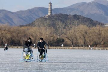 Dos turistas juegan con unas bicicletas adaptadas en la pista de hielo del Palacio de Verano de Pekín, un parque situado a unos 12 km del centro de la capital china. Desde 1998 está considerado como Patrimonio de la Humanidad por la Unesco, y desde ayer cuenta además con una gigantesca pista de hielo de 300.000 metros cuadrados.