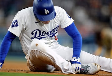 Freddie Freeman #5 of the Los Angeles Dodgers holds his right ankle after an injury running from home plate to first base on a ground out against first baseman Luis Arraez 