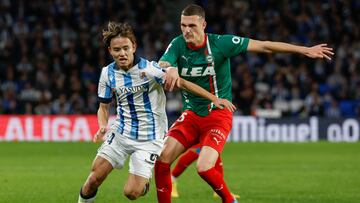 SAN SEBASTIÁN, 02/01/2024.- El centrocampista japonés de la Real Sociedad, Takefusa Kubo (i), disputa el balón ante el defensa del Alavés, Rafa Marín, durante el encuentro correspondiente a la jornada 19 de Laliga EA Sports que disputan hoy martes Real Sociedad y Alavés en el Reale Arena de San Sebastián. EFE / Juan Herrero.
