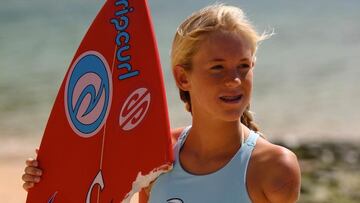 Bethany Hamilton de pequeña, con el brazo amputado y la tabla de surf que recibió el ataque de tiburón.