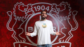 Borja Iglesias posa delante de una imagen del escudo del Bayer Leverkusen.