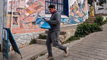 A man carries a bag as he walks down a hill since elevators are currently out of operation due to the new coronavirus pandemic, in Valparaiso, Chile, on June 08, 2020. - Amid the hills of Valparaiso, the new coronavirus advances and intimidates a port city without tourists or lifts to the slopes, which residents need to walk up and down carrying groceries to get home. (Photo by Martin BERNETTI / AFP)