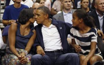 Barack Obama besa a la Primera Dama Michelle Obama durante un partido de baloncesto.