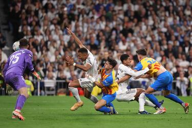 Kylian Mbappé y Jude Bellingham son sujetados dentro del área por defensores del Valencia durante una acción que terminó en penalti a favor del Real Madrid y abrió el marcador del encuentro con un gol de Mbappé.