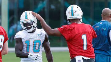 Tua Tagovailoa (right) taps the helmet of Tyreek Hill of the Miami Dolphins between drills during the Miami Dolphins Mandatory Minicamp at the Baptist Health Training Complex.