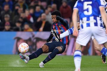 Una bota de un jugador de la Real Sociedad presiona a Alejandro Balde que lanza el balón mientras pierde el equilibrio.