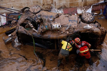 Los bomberos buscan posibles víctimas en el interior de un coche dañado tras las inundaciones, en Alfafar, Valencia. 