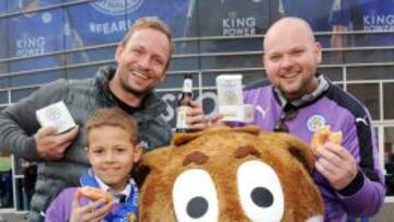 Varios fans posan con su cerveza y su donut junto a la mascota del club.