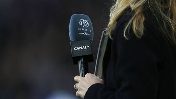 (FILES) In this file photograph taken on December 19, 2015, a journalist holds a microphone with the logo of French first football division Ligue 1 and Canal Plus television broadcaster before the French L1 football match between Caen (SM Caen) and Paris