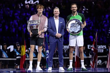 Jannik Sinner (a la izquierda con el título de campeón del Open de Australia), Daniil Medvedev (a la derecha con el título de subcampeón) posan junto al extenista Jim Courier.