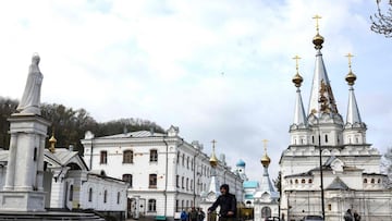 A man ride his bicycle near the damaged Sviatohirsk Cave Monastery, an Orthodox Christian monastery on the bank of the Seversky Donets River near the town of Sviatohirsk (Svyatohirsk), in eastern Ukraine on April 16, 2022. - Russia&#039;s military focus n