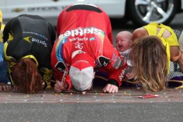 Kyle Busch, piloto del Skittles Toyota, con su esposa Samantha y su hijo Brexton besando el suelo después de ganar la NASCAR Sprint Cup Series Crown Royal Presents the Jeff Kyle 400 at the Brickyard