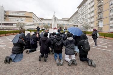 Fieles, monjas y diáconos asisten al rezo del Rosario bajo la escultura de San Juan Pablo II en la entrada principal del Hospital Policlínico A. Gemelli, donde el Papa Francisco recibe tratamiento por una neumonía doble, el 1 de marzo de 2025 en Roma, Italia. El Papa Francisco fue hospitalizado en Roma el 14 de febrero con bronquitis y posteriormente desarrolló neumonía pulmonar.