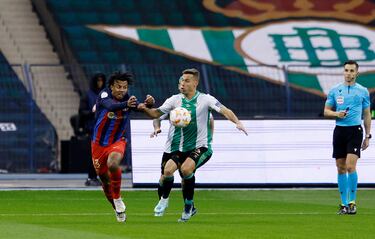 Jules Koundé y Sergio Canales disputan un balón mientras el árbitro, Carlos del Cerro Grande, observa la acción.