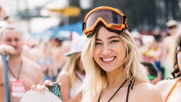 Una chica en bikini y tabla de snowboard participante del Boogel Woogel 2021 en la estación de esquí Rosa Khutor de Rusia sonríe a cámara.