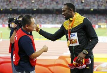 El cámara de televisión que se llevó en su 'Segway' por delante a Usain Bolt en la vuelta de honor de la final de 200m y el propio jamaicano se saludan tras el incidente.