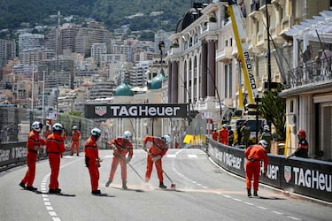 Los comisarios de carrera limpian la pista después del accidente de Checo Pérez.