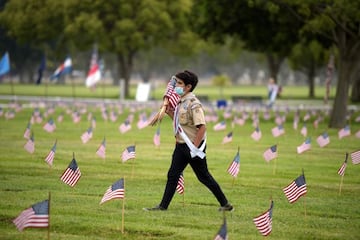 A boy scout places American flags at graves ahead of Memorial Day in the Los Angeles National Cemetery in Los Angeles, California on May 29, 2021. - The "Flags In" tradition takes place ahead of Memorial Day which honors service members who died while ser