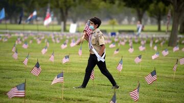A boy scout places American flags at graves ahead of Memorial Day in the Los Angeles National Cemetery in Los Angeles, California on May 29, 2021. - The "Flags In" tradition takes place ahead of Memorial Day which honors service members who died while ser