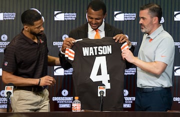 Mar 25, 2022; Berea, OH, USA;  Cleveland Browns quarterback Deshaun Watson looks at his new jersey along with general manager Andrew Berry, left and head coach Kevin Stefanski, right during a press conference at the CrossCountry Mortgage Campus. Mandatory Credit: Ken Blaze-USA TODAY Sports