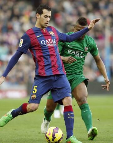 El centrocampista del FC Barcelona Sergio Busquets con el balón ante el delantero nigeriano del Levante Kalu Uche, durante el partido de la vigésimo tercera jornada de liga de Primera División.