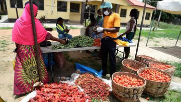 A tomato vendor (R) attends to buyer at a Primary School converted for a temporary makeshift food market established by Lagos State government for residents of the Ilupeju community in Lagos on April 3, 2020. - The Nigerian government has approved the est