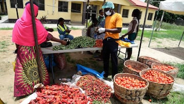 A tomato vendor (R) attends to buyer at a Primary School converted for a temporary makeshift food market established by Lagos State government for residents of the Ilupeju community in Lagos on April 3, 2020. - The Nigerian government has approved the est