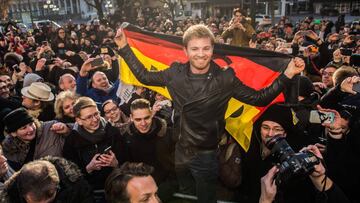 (FILES) This file photo taken on November 30, 2016 shows new Formula One World Champion Nico Rosberg (C) posing with a German flag as he meets with fans during a press event at his home town of Wiesbaden, western Germany.  Nico Rosberg announced on December 2, 2016 shock retirement days after winning Formula One title. / AFP PHOTO / dpa / Andreas Arnold / Germany OUT