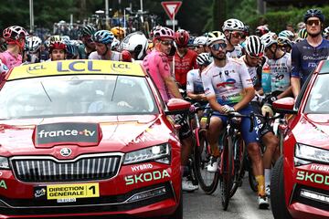 Ciclistas del pelot¨®n espectantes tras la detenci¨®n de la carrera debido al accidente masivo en el que cayeron al suelo m¨¢s de 30 ciclistas.