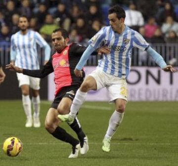 El centrocampista del Málaga CF Juanmi Jiménez lucha el balón con José Antonio "Verza", de la UD Almería, durante el partido de la decimoséptima jornada de Liga en Primera División 