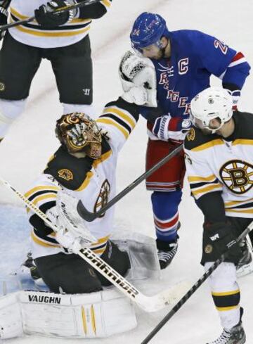 Ryan Callahan de los New York Rangers recibe un golpe en la cara del portero de Boston Tuukka Rask.