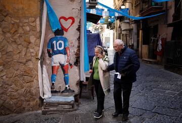 A couple walk past a mural of Diego Maradona in the Spanish quarter, ahead of Napoli potentially winning Serie A.