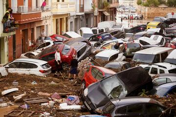 Vecinos observan los autos amontonados luego de ser arrastrados por las inundaciones en Valencia, España.