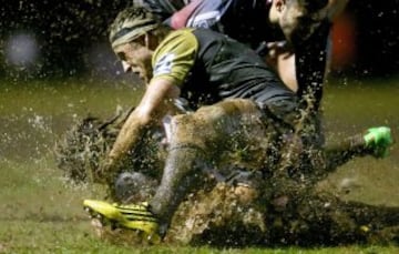 Aunque en la imagen no se ve claro, debajo del jugador de los Hurricanes Hugh Renton, hay un jugador contrario y una pelota. Aunque por momentos parezca que Renton est芍 luchando contra el barro.