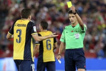 El colegiado Gil Manzano muestra la tarjeta amarilla al defensa brasileño del Atlético Madrid, Guilerhme Siqueira, durante el encuentro de la 5ª jornada de la liga de Primera División que se esta disputando esta noche en el estadio de los juegos Mediterraneos de Almeria.
