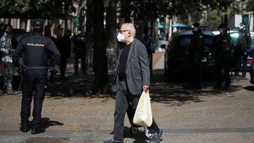 Un hombre regresa a su casa después de haber hecho la compra en medio de la cuarentena y entre los policías.