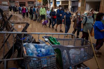 Residentes de Paiporta esperan para recibir agua entre los restos de lodo y los estragos de la DANA.