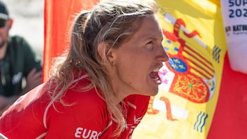 La surfista Amandine Chazot durante el EuroSUP 2022 ante una bandera española, gritando.