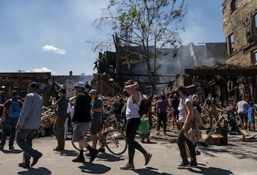 MINNEAPOLIS, MN - MAY 30: People work to clean up outside a burned building on May 30, 2020 in Minneapolis, Minnesota. Buildings and businesses around the Twin Cities have been looted and destroyed in the fallout after the death of George Floyd while in police custody. Police Officer Derek Chauvin has been charged with third-degree murder and manslaughter in Floyd's death. Stephen Maturen/Getty Images/AFP == FOR NEWSPAPERS, INTERNET, TELCOS & TELEVISION USE ONLY ==