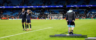Lucas Vázquez y Jude Bellingham celebran mientras el operario del césped del Etihad Stadium realiza su labor.