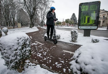 Una mujer conduce un patinete eléctrico por una calle cubierta de nieve en Burgos, Castilla y León (España). La provincia está en alerta debido a que la cota de nieve ha bajado a los 400 metros y se esperan nevadas generalizadas. 
