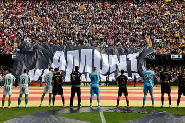 Los jugadores del Valencia y del Real Betis observan el despliegue de una pancarta momentos antes del partido.