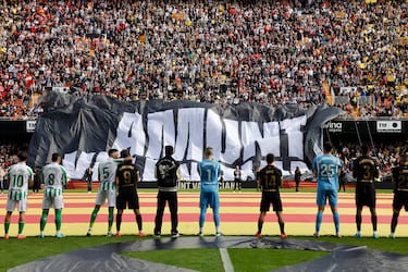 Los jugadores del Valencia y del Real Betis observan el despliegue de una pancarta momentos antes del partido.