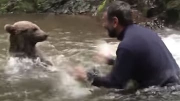 El explorador turco Cemal Gulas salpica a un oso salvaje en un río en la Repúblia de Áltai (Rusia).
