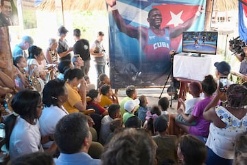 The mother of Cuban wrestler Mijain Lopez, Leonor Nunez (2nd L, white blouse), watches the fight of her son at the Paris 2024 Olympic Games on a TV with friends and neighbours at her home in the town of Herradura, Pinar del Rio province, Cuba, on August 6, 2024. Cuban wrestler Mijain Lopez made Olympic history on Tuesday when he became the first athlete to win five consecutive individual golds in the same event, bettering the records of Games icons such as Carl Lewis and Michael Phelps. (Photo by YAMIL LAGE / AFP)